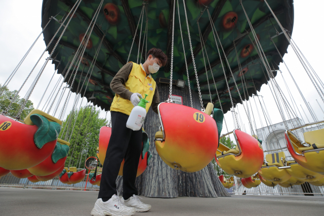 30일 오후 서울 광진구 어린이대공원 놀이동산에서 한 관계자가 이용객들의 안전을 위해 놀이기구를 소독하고 있다. 정부는 코로나19 확산세 차단을 위해 현행 
