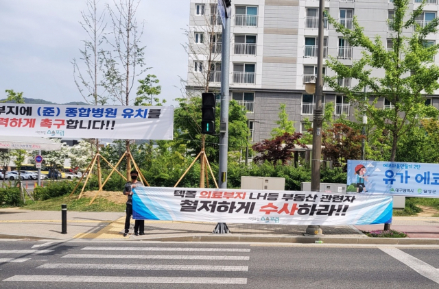 대구 테크노폴리스 의료시설용지가 비의료인에게 분양되면서 7년째 공터로 남아 있는 가운데 종합병원이나 응급실이 없어 주민들이 불편을 겪고 있다. 테크노폴리스 아파트단지에 이와 관련된 현수막이 붙고 릴레이 1인 시위가 이뤄지고 있다. 독자제공