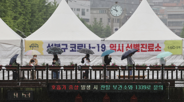 지난 15일 하루 동안 서울에서 발생한 신종 코로나바이러스 감염증(코로나19) 신규 확진자 수가 213명이라고 서울시가 16일 밝혔다. 사진은 16일 오전 서울 성북구청 앞에 설치된 임시선별진료소에서 시민들이 우산을 쓰고 검사를 위해 대기해 있다. 연합뉴스