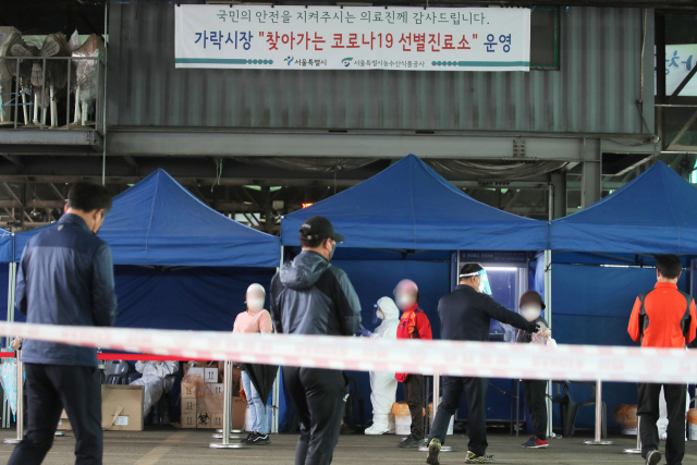 21일 오후 서울 송파구 가락농수산물종합도매시장에 설치된 선별진료소에서 상인 등 시장 종사자들이 코로나19 검사를 받고 있다. 지난 18일 시장 종사자 1명이 확진된 뒤 20일 6명이 추가 확진돼 가락시장 관련 누적 확진자는 총 14명으로 늘었다. 연합뉴스