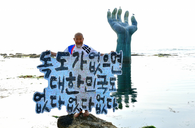 지난 2일 경북 포항 남구 호미곶 손 조형물 앞에서 서예가 김동욱 씨가 일본 지도에 독도를 삭제하라는 퍼포먼스를 하고 있다. 연합뉴스