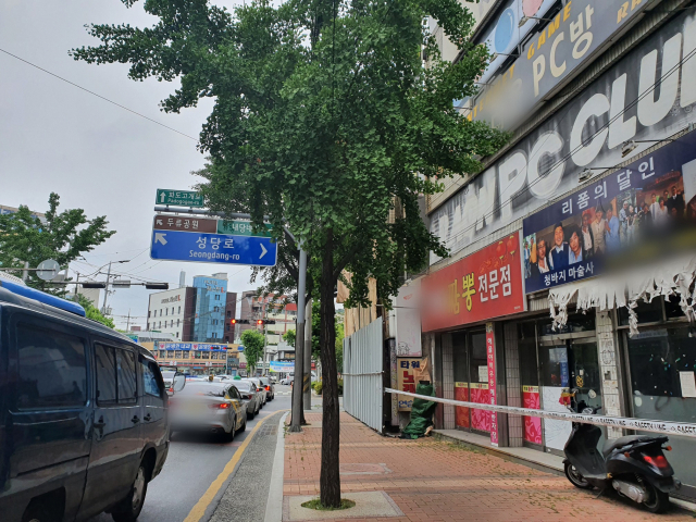 대구 남구 대명동 성당네거리에 위치한 철거 예정 중인 건물. 3~4m 떨어진 도로에 신호를 받는 차량들이 줄지어 있다. 배주현 기자