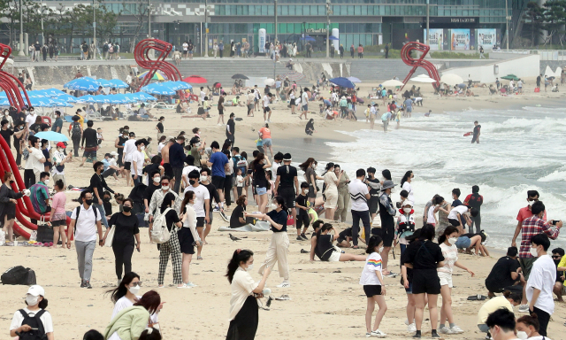 부산지역 해수욕장 전면 개장 첫 주말인 4일 해운대해수욕장에서 피서객들이 더위를 식히고 있다. 부산은 1일부터 새로운 사회적 거리두기가 적용됐으나 해운대해수욕장과 송정해수욕장에서는 4인까지만 모임이 가능하다. 부산 해수욕장에서는 백신 접종자를 포함해 모든 방문객이 마스크를 24시간 써야 하고 해수욕장별 고유 번호(안심콜)로 전화를 해 방문 기록을 남겨야 한다. 파라솔은 2m 이상 간격으로 설치해야 한다. 연합뉴스