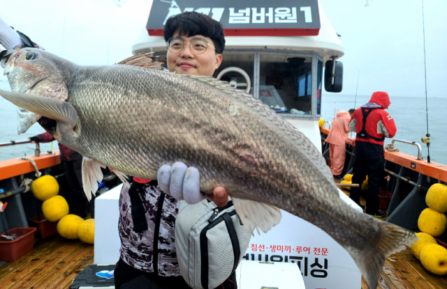 한 낚시인이 끌어올린 78 cm 크기의 민어를 들어보이며 흐뭇해 하고 있다.