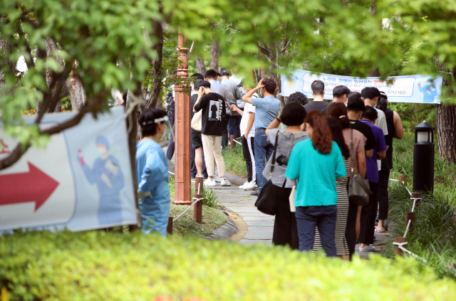 13일 대구 중구 국채보상공원에 마련된 임시선별진료소에서 시민들이 뜨거운 햇볕을 피해 숲길에서 신종 코로나바이러스 감염증(코로나19) 검사를 기다리고 있다. 연합뉴스