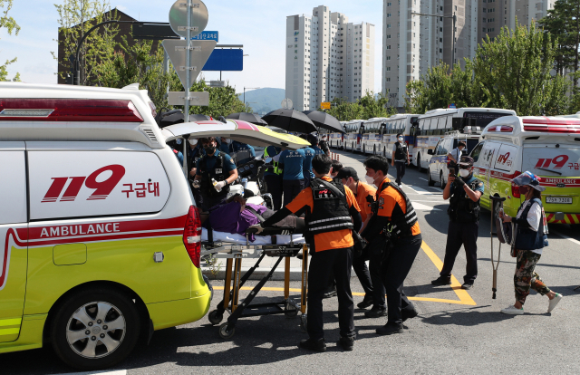 23일 강원 원주시 국민건강보험공단 인근에서 열린 고객센터 노조 직접 고용 촉구 결의대회에서 한 참가자가 어지러움을 느껴 구급차로 이송되고 있다. 정부는 이날 집회에서 신종 코로나바이러스 감염증 방역수칙 위반을 발견하면 엄정 대응하겠다고 밝혔다. 연합뉴스