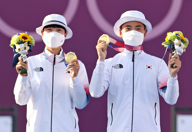 양궁 국가대표 김제덕과 안산이 24일 일본 도쿄 유메노시마 공원 양궁장에서 열린 도쿄올림픽 혼성 결승전에서 금메달을 획득한 후 메달을 보이고 있다. 연합뉴스