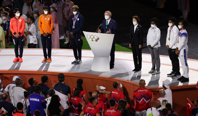 8일 도쿄 신주쿠 국립경기장에서 열린 2020 도쿄올림픽 폐회식에서 토마스 바흐 IOC 위원장이 축사를 하고 있다. 좌우는 하시모토 세이코 조직위원장과 각 대륙 대표 선수들. 연합뉴스