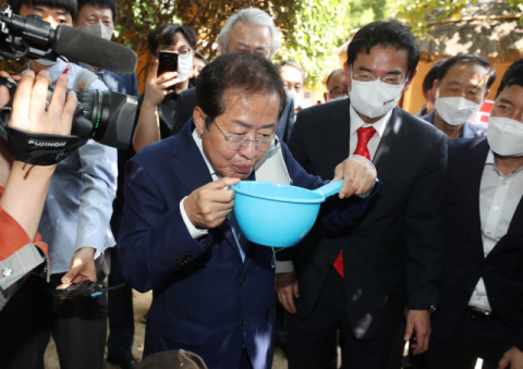 국민의힘 대권주자인 홍준표 의원이 12일 경북 구미시 상모동에 있는 박정희 전 대통령의 생가를 찾아 박 전 대통령이 사용하던 펌프에 마중물을 붓고 있다. 연합뉴스