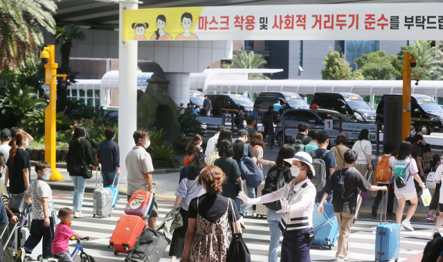 본격적인 추석 연휴가 시작한 18일 제주국제공항에 도착한 관광객들이 렌터카 주차장으로 향하고 있다. 출입문 앞 현수막에 