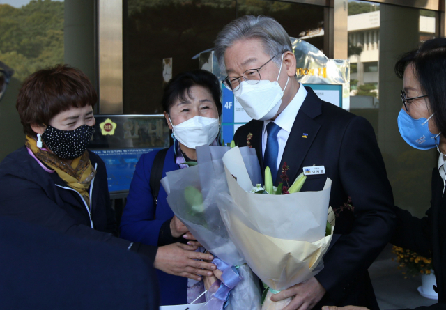 더불어민주당 대선 후보인 이재명 경기지사가 25일 오후 경기 수원 경기도의회 입구에서 지지자들로부터 꽃다발을 선물 받고 있다. 연합뉴스