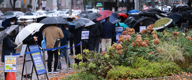 8일 오전 서울 송파구 보건소 코로나19 선별검사소에서 시민들이 검사를 받기 위해 우산을 쓴 채 차례를 기다리고 있다.연합뉴스