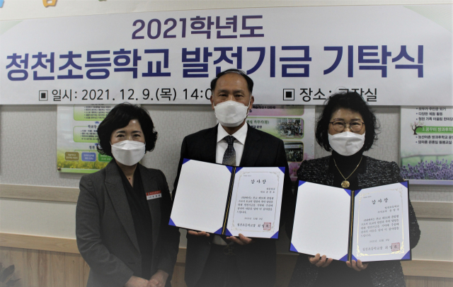 (왼쪽부터)청천초교 최영희 교장과 학교 졸업생인 송중호·양숙 남매가 학교발전기금 1천만원을 기탁한 후 감사장을 받고 있다. 청천초등학교 제공