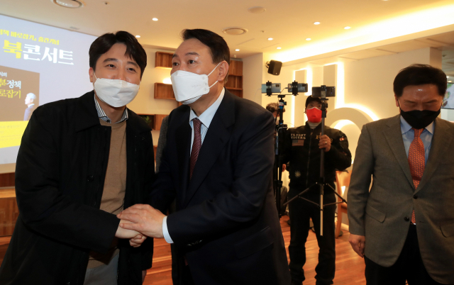 국민의힘 윤석열 대선 후보와 이준석 대표가 9일 오후 서울 여의도 한 카페에서 열린 김근식 교수의 대북정책 관련 북콘서트에 참석, 기념 촬영을 한 뒤 악수하고 있다. 연합뉴스