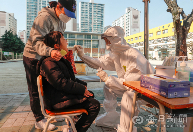 개학 후 학생·교직원 확진자가 폭증하자 대구시교육청이 8일 학교로 찾아가는 이동식PCR검사팀 운영을 시작해 시내 한 초등학교에서 진단검사를 받으려는 학생과 교직원이 차례를 기다리고 있다. 우태욱 기자 woo@imaeil.com