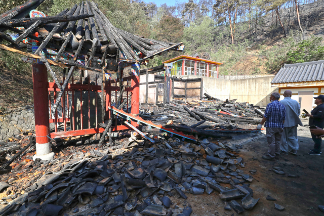 29일 오전 울진군 울진읍 보광사 대웅전이 산불로 소실돼 사찰 관계자들이 망연자실한 상태로 돌아보고 있다. 연합뉴스