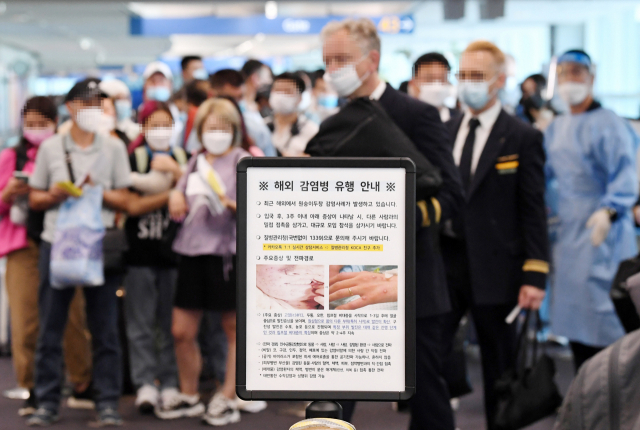 27일 오전 인천국제공항 제1터미널 입국장에 해외입국자들이 검역을 받기 위해 대기하고 있다. 승객들 앞에는 원숭이두창 관련 안내문이 세워져 있다. 연합뉴스