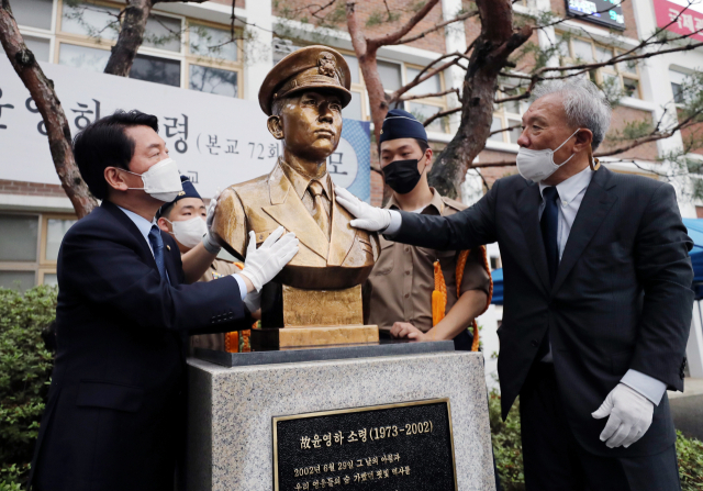 국민의힘 안철수 의원(왼쪽)이 29일 오후 인천시 연수구 송도고등학교에서 열린 윤영하 소령 20주기 추모식에 참석해 윤 소령 흉상에 있는 빗물을 닦아내고 있다. 연합뉴스