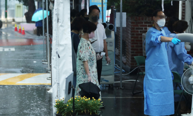 13일 오전 서울 종로구 보건소 선별진료소에서 시민들이 관계자의 안내를 받으며 코로나19 검사를 기다리고 있다. 중앙방역대책본부에 따르면 이날 0시 기준 신규확진자는 모두 4만266명으로 63일 만에 다시 4만 명대를 기록했다. 연합뉴스