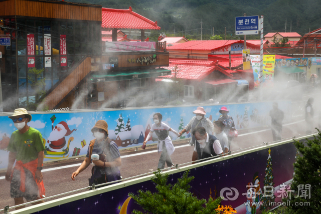 24일 봉화군 분천역 산타마을을 찾은 관광객들이 쿨링 포그가 뿜어져 나오는 축제장 입구를 통과하고 있다. 코로나19 재유행 속에서도 휴가철을 맞아 경북도에서는 봉화 분천한여름축제를 시작으로 다음달 말까지 다양한 축제가 펼쳐질 예정이다. 우태욱 기자 woo@imaeil.com