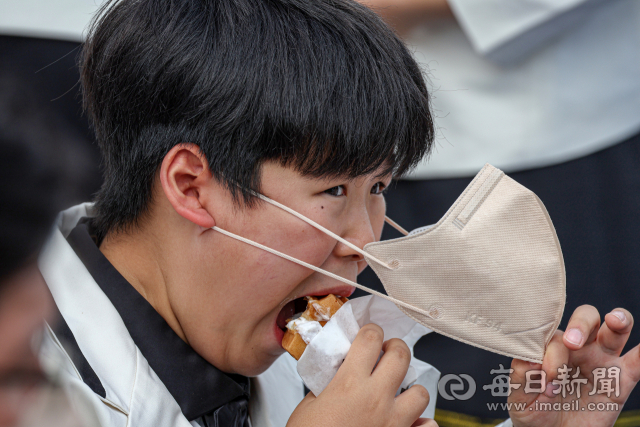 23일 오후 대구 수성못 일대에서 한 어린이가 마스크를 잡아당기며 힘겹게 와플을 먹고 있다. 정부는