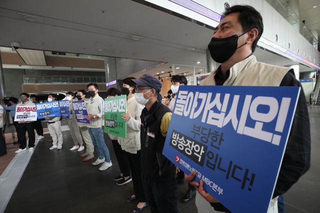 국민의힘 의원들이 윤석열 대통령 해외순방 관련 보도와 관련해 문화방송을 항의 방문한 28일 오전 서울 마포구 문화방송 본사 로비에서 전국언론노동조합 MBC본부 노조원들이 피켓을 들고 있다. 연합뉴스