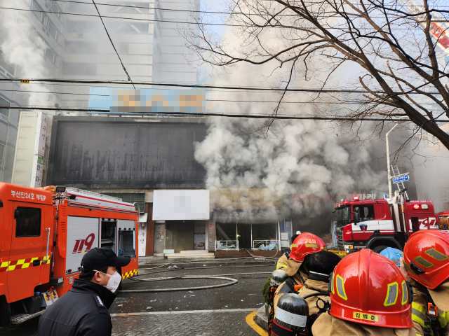 9일 오전 부산 부산진구의 한 오피스텔 주차타워에 불이 났다. 부산소방재난본부는 화재 발생 50분 만에 큰 불길을 잡고, 대응 2단계를 발령해 화재 진화에 주력하고 있다. 30여 명이 연기를 마시고 인근 주택가 등에 대피령이 내려졌다. 사진은 불티가 인근 상가 건물로 옮겨붙어 연기가 나는 모습. 연합뉴스