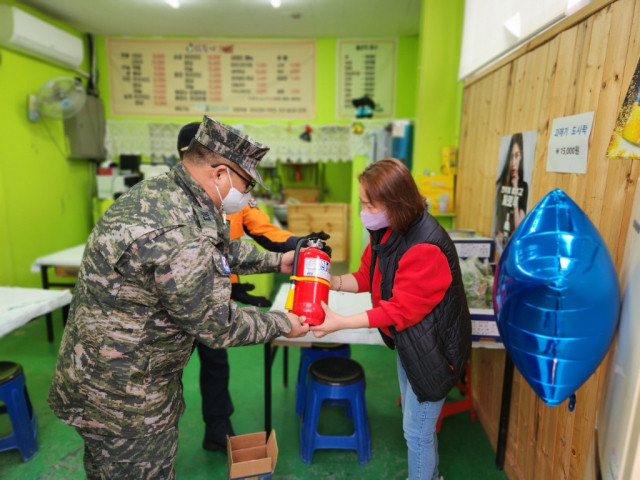 지난달 23일 오후 9시쯤 포항시 남구 동해면 도로 갓길에서 발생한 화재를 진압한 해병대 제1사단 소속 최춘만 상사가 포항남부소방서 직원들과 함께 불이 난 장소 인근 상인들에게 소화기를 전달하고 있다. 해병대 제1사단 제공.