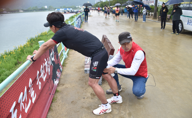 철인3종경기의 마지막 구간인 10km 달리기 구간에서 선수들에게 스프레이파스를 뿌려주고있다.