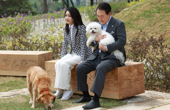 윤석열 대통령과 부인 김건희 여사가 지난 4일 서울 용산 대통령실의 앞마당에 조성된 용산 어린이정원 개방 기념식수를 마친 뒤 써니와 은퇴안내견 새롬이(왼쪽)와 휴식을 취하고 있다. 연합뉴스