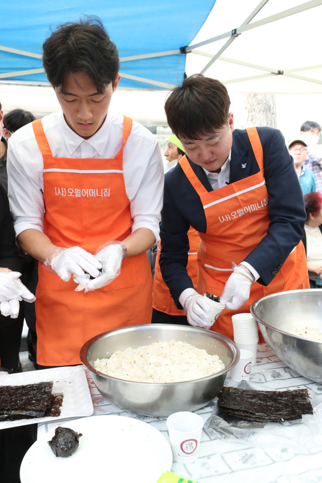 전직 대통령 고 전두환씨의 손자 전우원씨가 17일 광주 동구 금남로에서 열린 5·18 시민 난장 오월 주먹밥 체험 부스에서 국민의힘 이준석 전 대표와 주먹밥을 만들고 있다. 연합뉴스