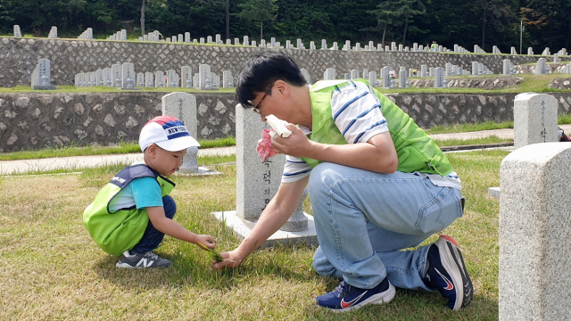 현대엔지니어링 임직원 및 임직원 가족이 국립서울현충원에서 묘역 정화 봉사활동을 하고 있다.