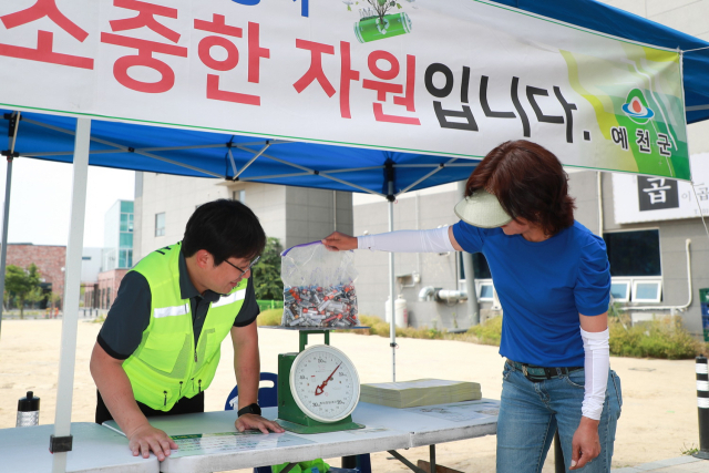 폐건전지 교환 행사에 폐건지를 갖고 온 주민이 건전지의 무게를 재고 있다. 예천군 제공