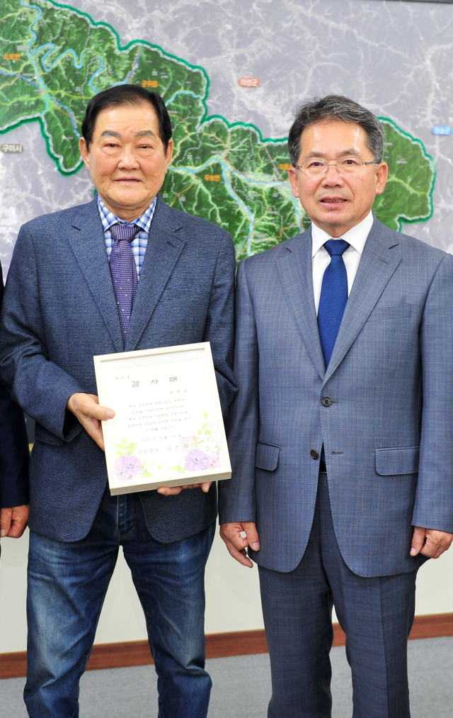 김진열(오른쪽) 경북 군위군수가 고향사랑기부제에 500만원 고액을 기부한 최동오(왼쪽) 씨에게 감사패를 전달하고 기념 사진을 촬영하고 있다. 군위군 제공