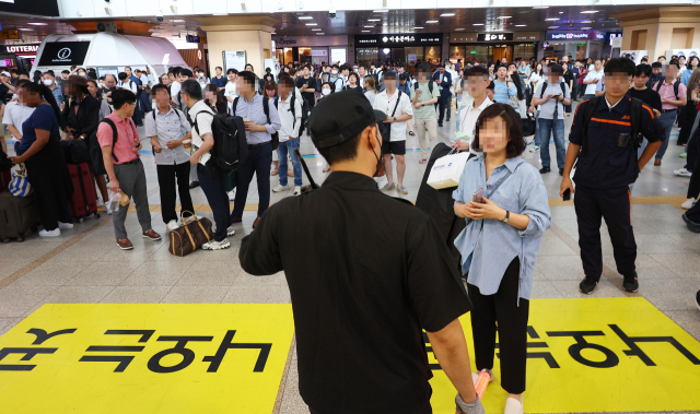 서울지하철 1호선 가산디지털단지역 인근 선로에서 발생한 인명사고로 지하철 1호선 및 KTX 열차 운행이 지연된 26일 오전 서울역에서 관계자가 시민들에게 안내하고 있다. 경찰과 코레일 등에 따르면 이날 오전 5시30분께 서울발 부산행 KTX 열차 선로에 신원을 알 수 없는 남성이 무단 진입해 숨졌다. 연합뉴스