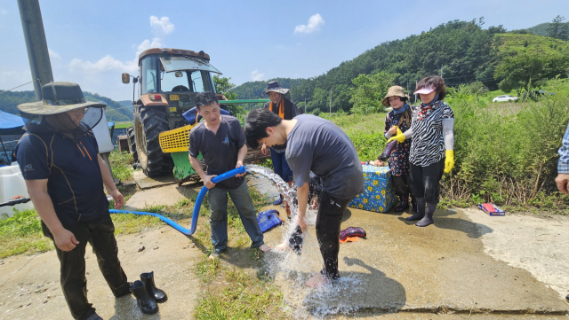 30일 오후 예천 감천면 농가 피해 복구현장. 휴가를 반납하고 경남 김해에서 예천으로 아내와 두 자녀와 함께 봉사를 온 구영길(51) 씨가 아들에게 물을 뿌려 더위를 쫓아주고 있다. 윤영민 기자