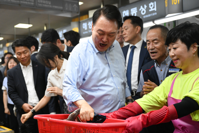 윤석열 대통령이 27일 부산 중구 자갈치시장에서 장어를 직접 손으로 잡아 보다 장어가 물자 놀란 표정을 짓고 있다. 연합뉴스