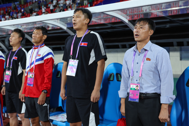 21일 오후 중국 저장성 진화 저장성사범대동쪽경기장에서 열린 2022 항저우 아시안게임 남자 축구 예선 F조 2차전 키르기스스탄과 북한의 경기에 앞서 북한 신용남 감독과 코치진이 국가를 부르고 있다. 연합뉴스