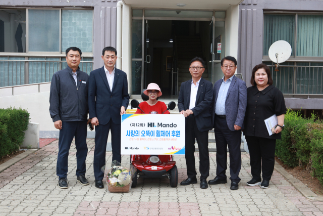 김근도(왼쪽 두번째) HL만도 서스펜션 BU 경영지원실장과 장찬옥(오른쪽 세번째) 한국교통안전공단 교통안전본부장이 지원 사업에 선정된 가정을 방문해 휠체어를 전달하고 있다. 한국교통안전공단 제공