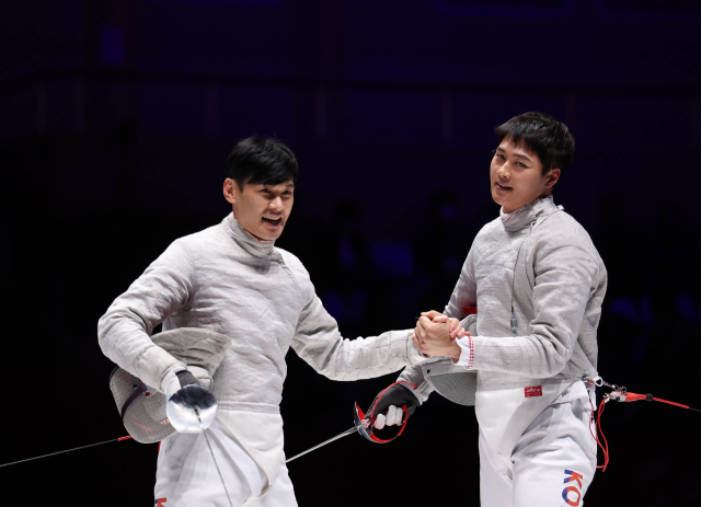 25일 중국 항저우 전자대학 체육관에서 열린 2022 항저우 아시안게임 펜싱 남자 사브르 개인전 결승에서 우승을 차지한 오상욱(오른쪽)과 구본길이 악수를 하며 인사하고 있다. 연합뉴스