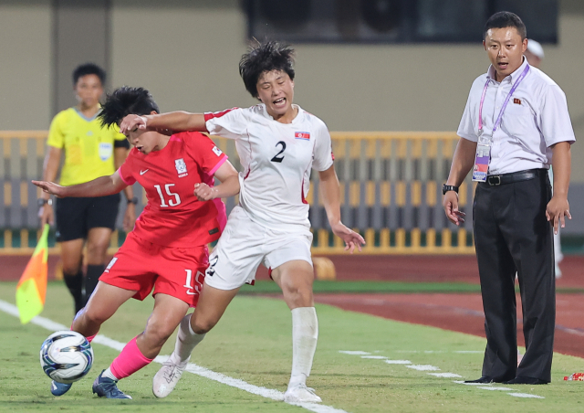 30일 중국 원저우 스포츠센터 스타디움에서 열린 2022 항저우 아시안게임 여자축구 8강전 한국과 북한의 경기. 후반 북한 리유일 감독이 대한민국 천가람과 북한 리명금의 볼 다툼 모습을 바라보고 있다. 연합뉴스