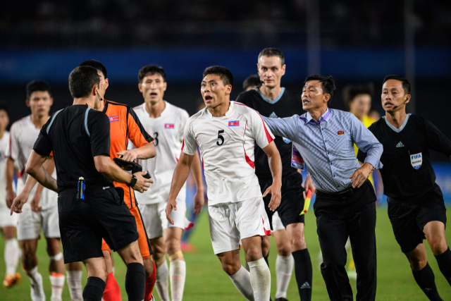 N북한 남자축구 선수들이 1일 일본과의 8강전에서 패배한 뒤 심판에게 달려가 격렬하게 항의하고 있다. 연합뉴스