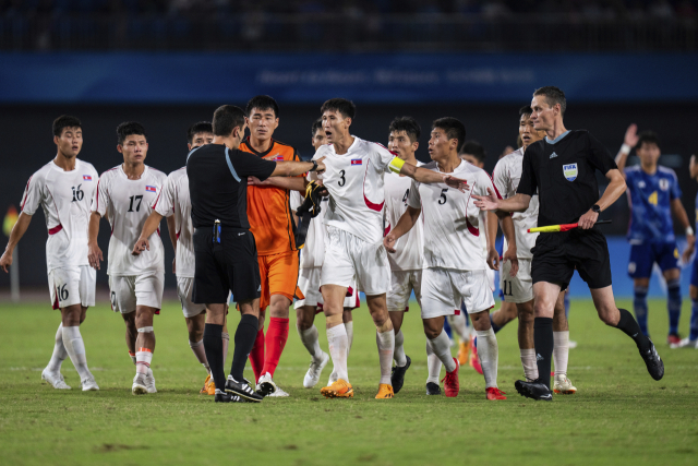 북한 남자축구 선수들이 1일 일본과의 8강전에서 패배한 뒤 심판에게 달려가 격렬하게 항의하고 있다. 연합뉴스