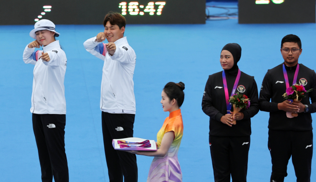 4일 중국 항저우 푸양 인후 스포츠센터에서 열린 2022 항저우 아시안게임 양궁 리커브 혼성전에서 금메달을 획득한 임시현(왼쪽)과 이우석이 시상대에 올라 세리머니를 하고 있다. 연합뉴스