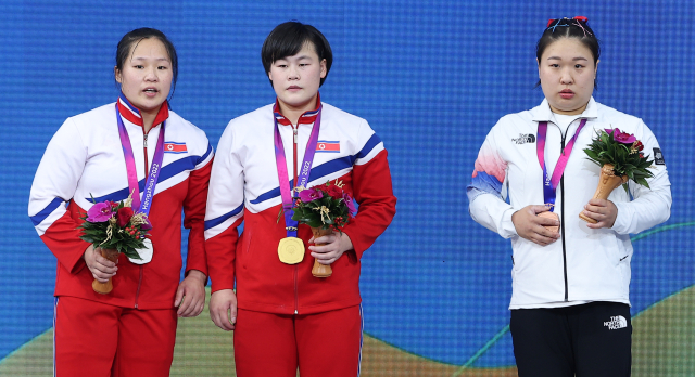 5일 중국 항저우 샤오산 스포츠센터에서 열린 2022 항저우 아시안게임 역도 여자 76kg급 그룹 A 경기에서 동메달을 차지한 대한민국 김수현(오른쪽)이 시상식에서 금메달 북한 송국향(가운데), 은메달 북한 정춘휘와 함께 기념촬영을 하기 위해 함께 시상대에 올라 있다. 연합뉴스