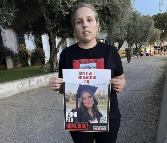 하마스에 인질로 잡힌 딸의 얼굴 사진이 그려진 티셔츠를 입고 무사 귀환을 바라는 팻말을 들고 선 마르시아노 상병의 어머니. 엑스(구 트위터)
