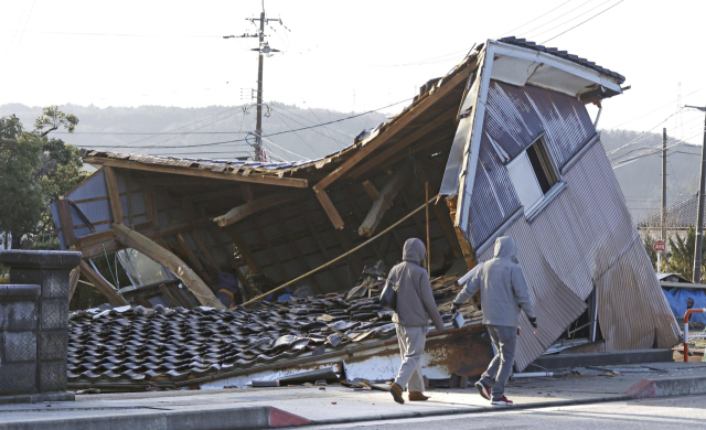 2일 일본 이시카와현 시카마치에서 사람들이 지진으로 무너진 건물을 지나가고 있다. 새해 첫날인 전날 이시카와현에서 규모 7.6의 강진이 발생한 뒤 주변 지역에서 여러 차례 여진이 관측됐다. 연합뉴스