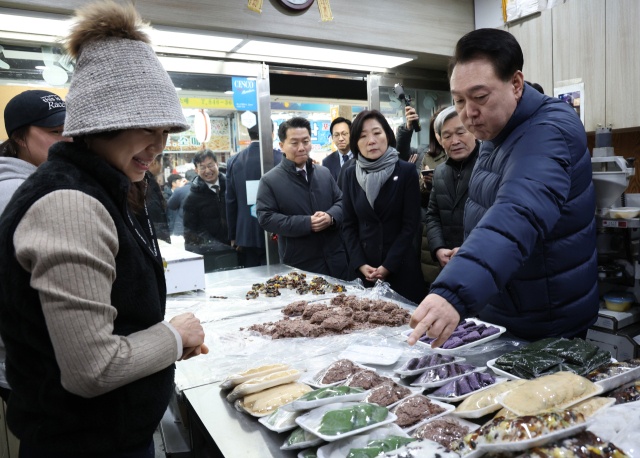 윤석열 대통령이 25일 경기도 의정부시 의정부제일시장을 찾아 떡 가게에서 떡을 고르고 있다. 연합뉴스