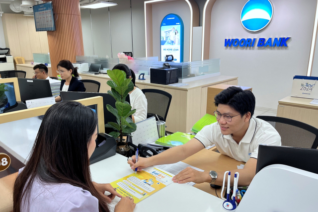 베트남우리은행 푸미흥 지점에서 직원이 내점 고객에게 우리루키 프로젝트 베트남 해외의료 지원사업에 대해 안내하고 있다. 우리금융