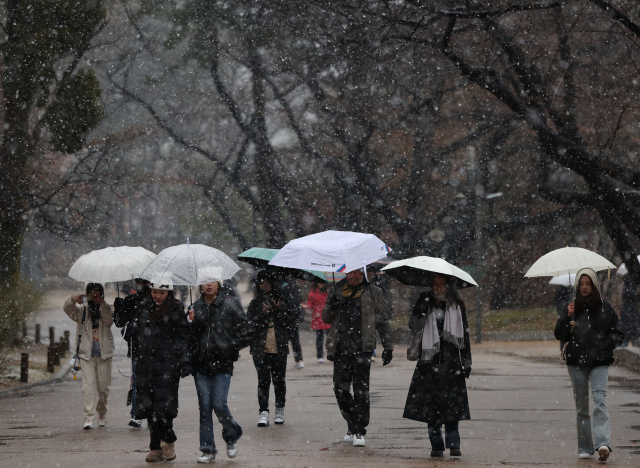 전국 대부분 지역에 비나 눈이 내린 15일 오후 서울 중구 덕수궁에서 외국인 관광객이 우산을 쓰고 걷고 있다. 연합뉴스